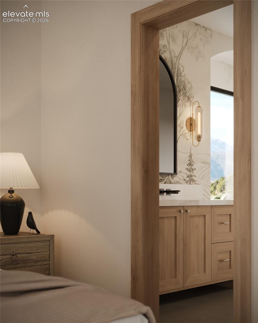 Wood-finish door frame, wood-finish vanity with paneling and drawer fronts, rectangular vanity mirror, wall-mounted light fixture, and stone countertop