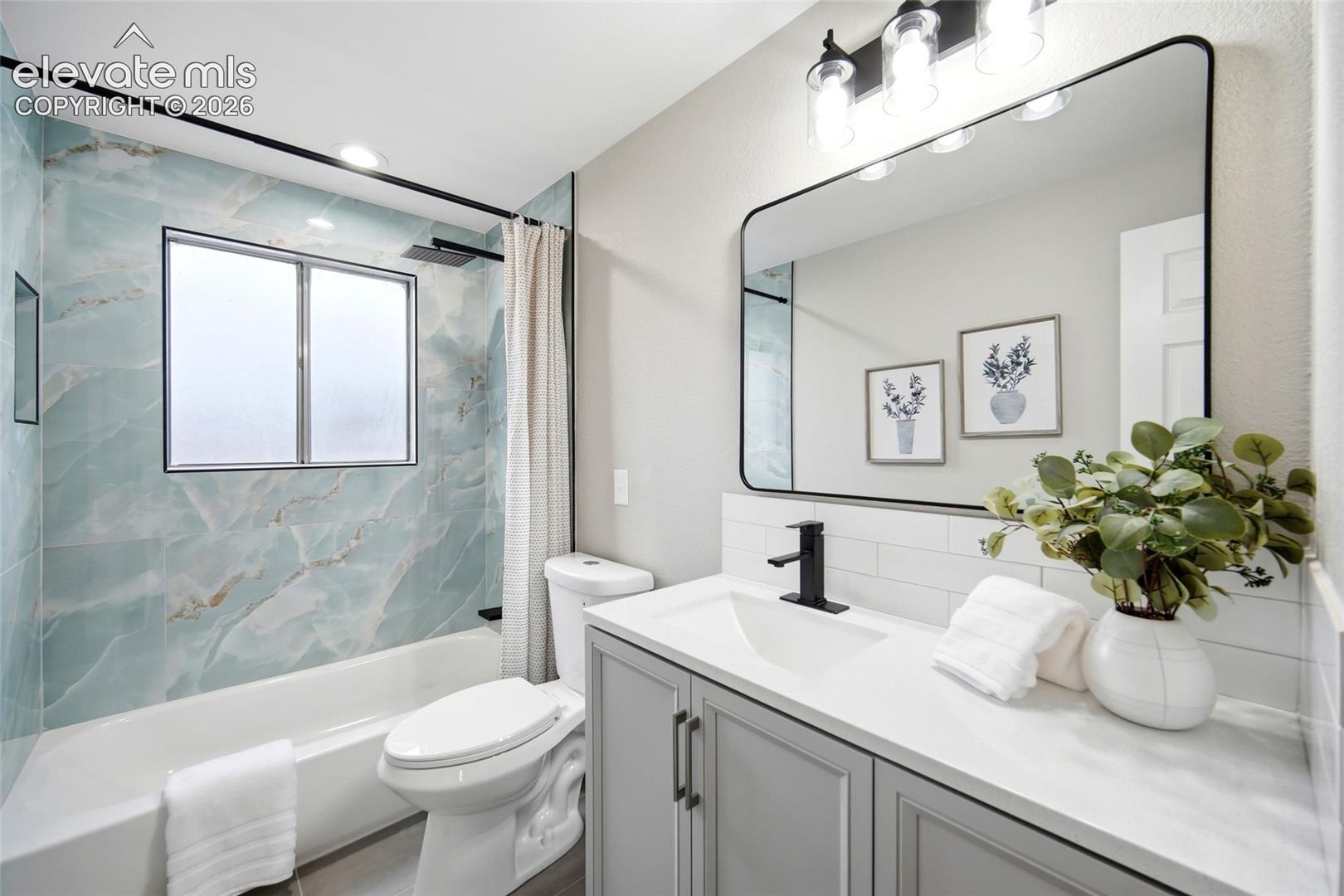 Light gray vanity with dual cabinet doors and matte black hardware, white countertop, rectangular undermount sink with a matte black faucet, and a large black-framed mirror