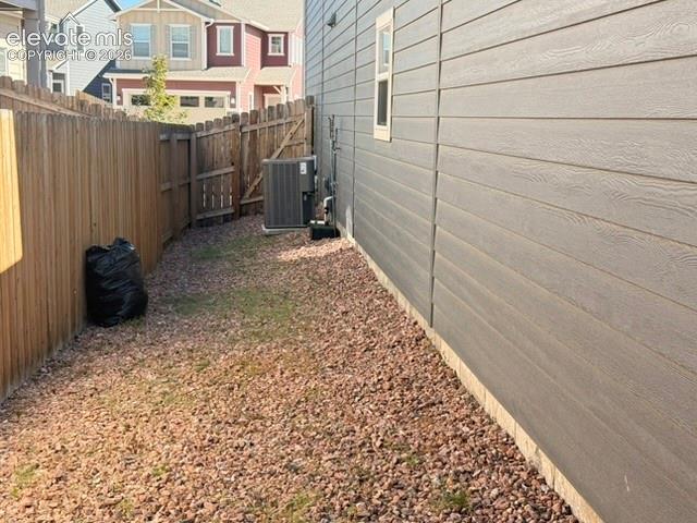Horizontal siding with a textured finish, wood privacy fence, and gravel ground cover