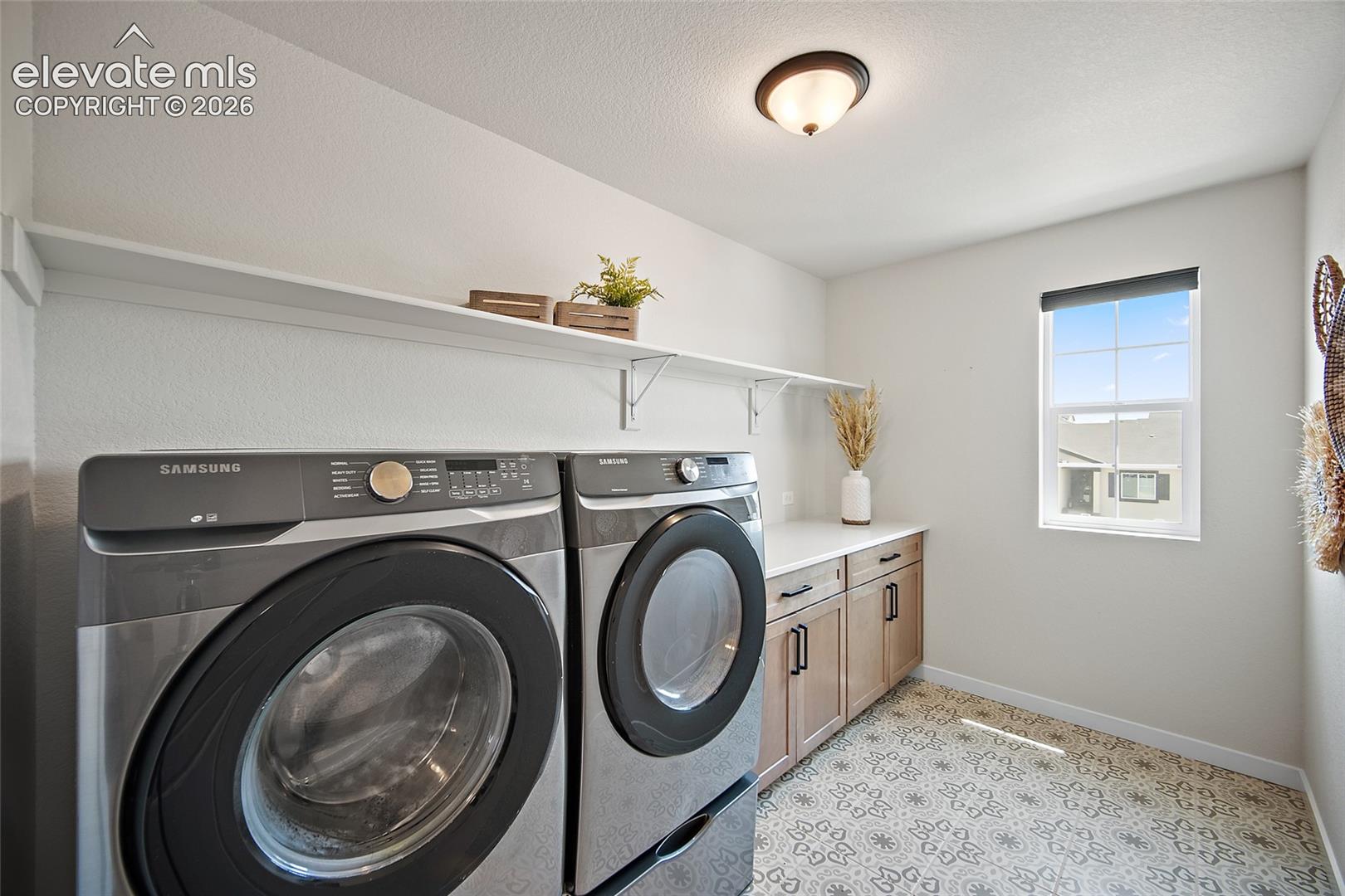 Built-in cabinetry with dark hardware, white countertop, white wall shelving, and patterned floor tile
