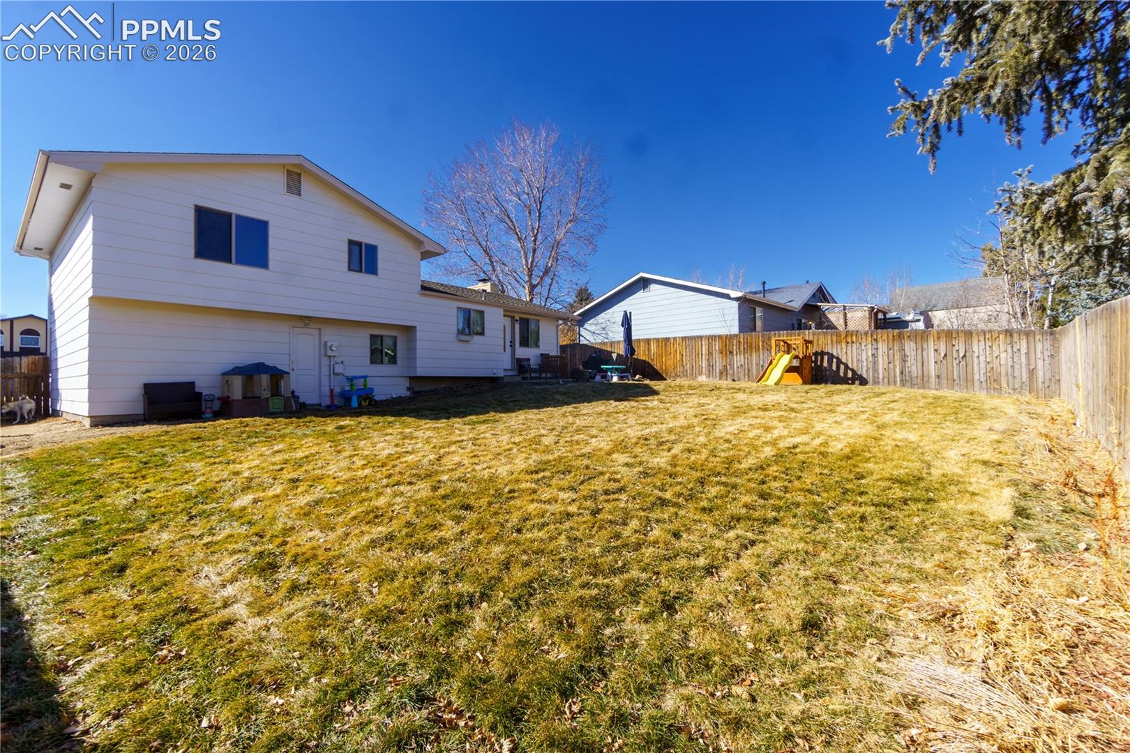 Back of property with a fenced backyard and a lawn