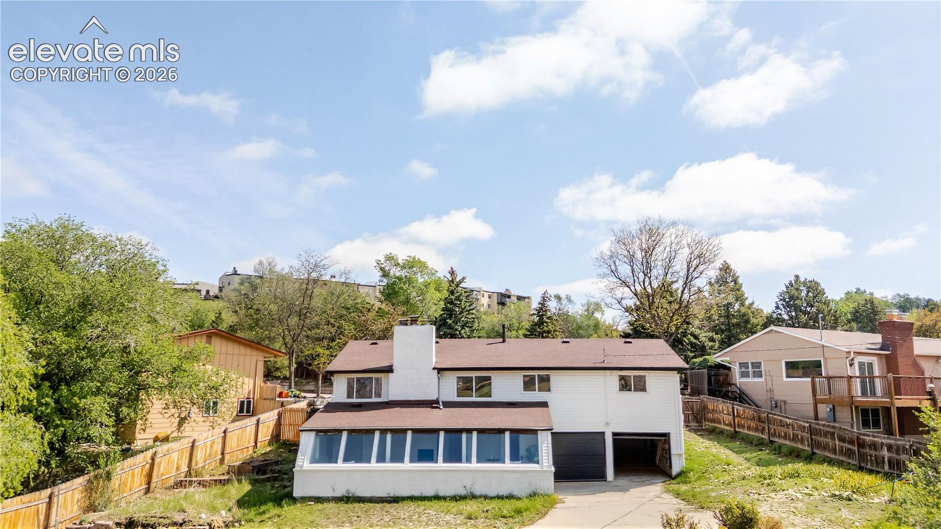 Two-story residence with a lower-level sunroom, two-car garage, and a central chimney