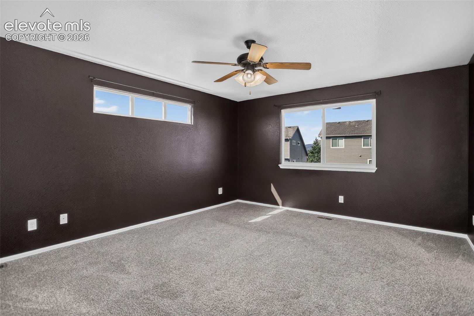 Wall-to-wall carpeting, ceiling fan with light fixture, and multiple windows with white trim