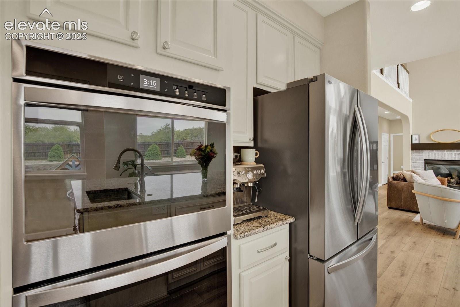 Stainless steel double wall ovens, French door refrigerator, shaker-style cabinetry, and stone countertops