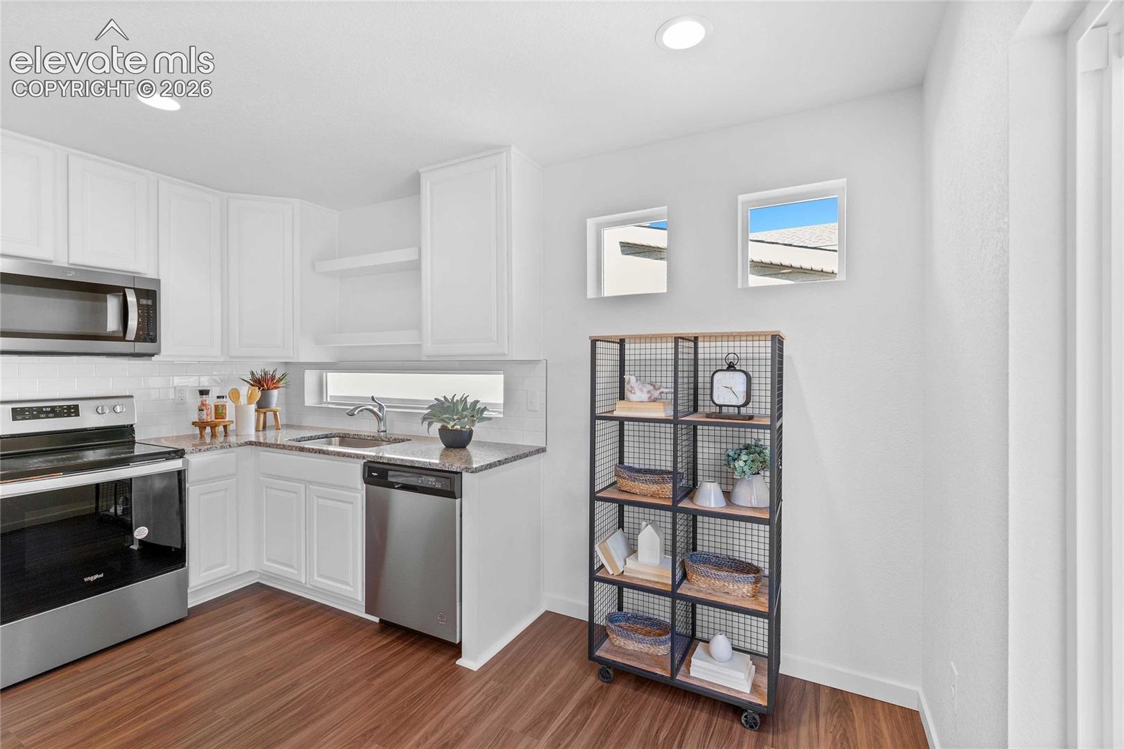 White cabinetry, stainless steel appliances, wood-finish flooring, recessed lighting, and a backsplash
*photos of a model home*