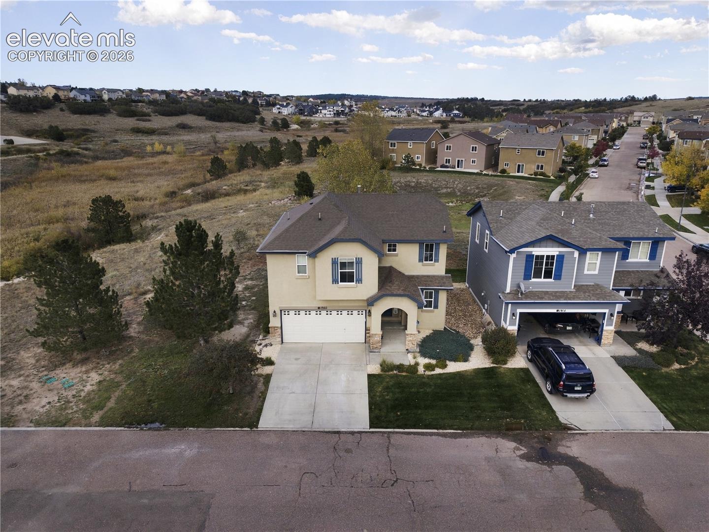 Two-story residence featuring a stucco exterior, multi-gabled roofline, concrete driveway, and attached two-car garage