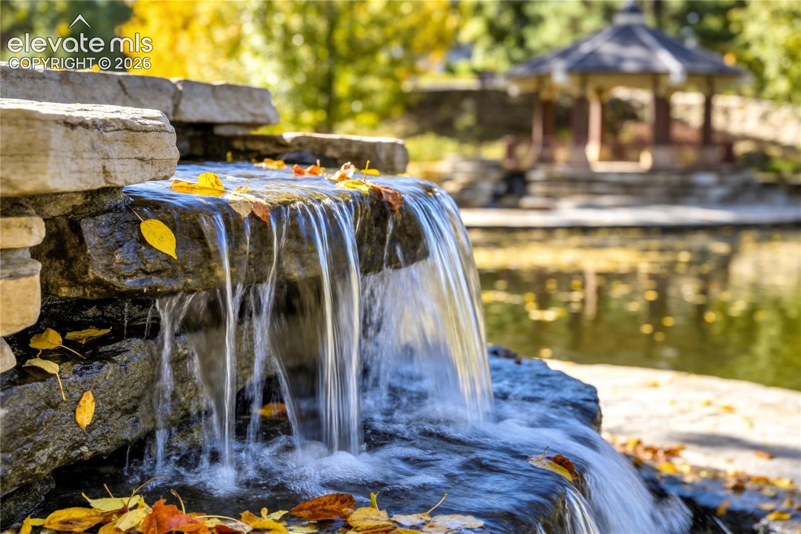 Cascading water flows over a natural stone waterfall, adding texture, movement + a soothing atmosphere to Stone Crossing's beautifully designed neighborhood landscape.