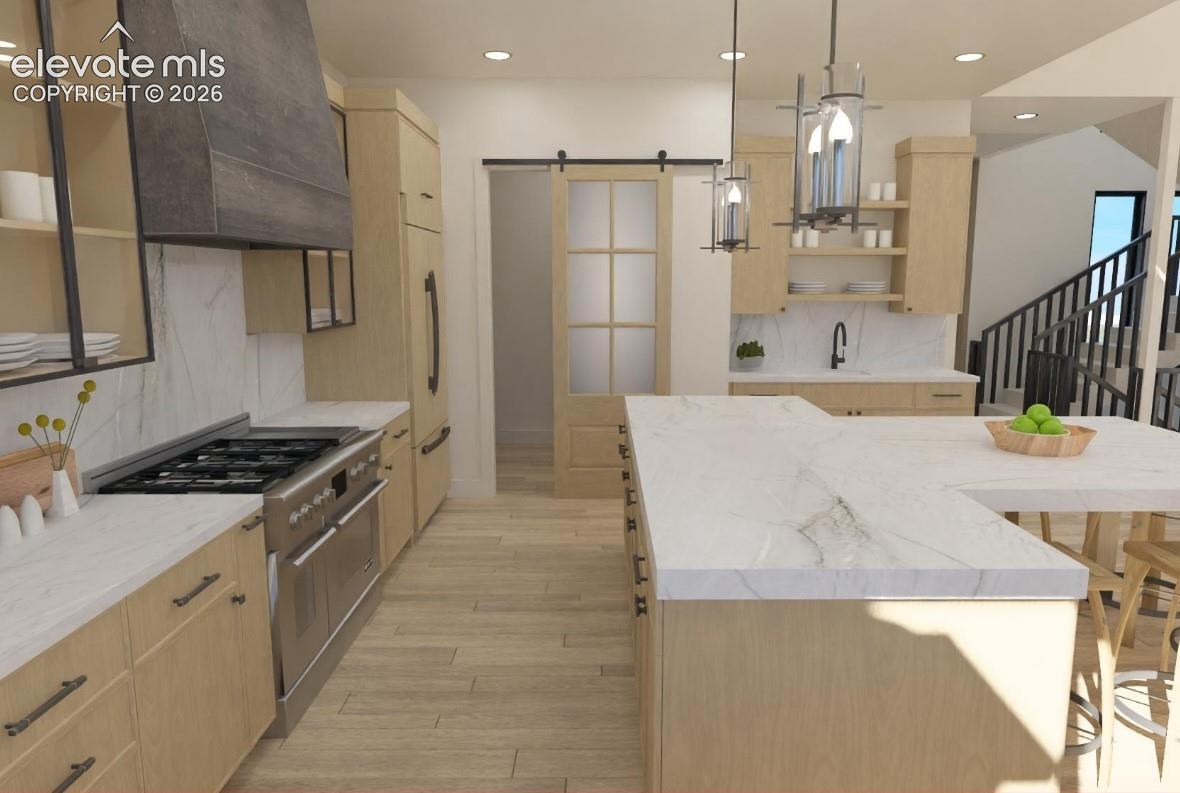 Kitchen featuring light wood-finish cabinetry, stainless steel appliances, a large center island with a white countertop, and a sliding barn door