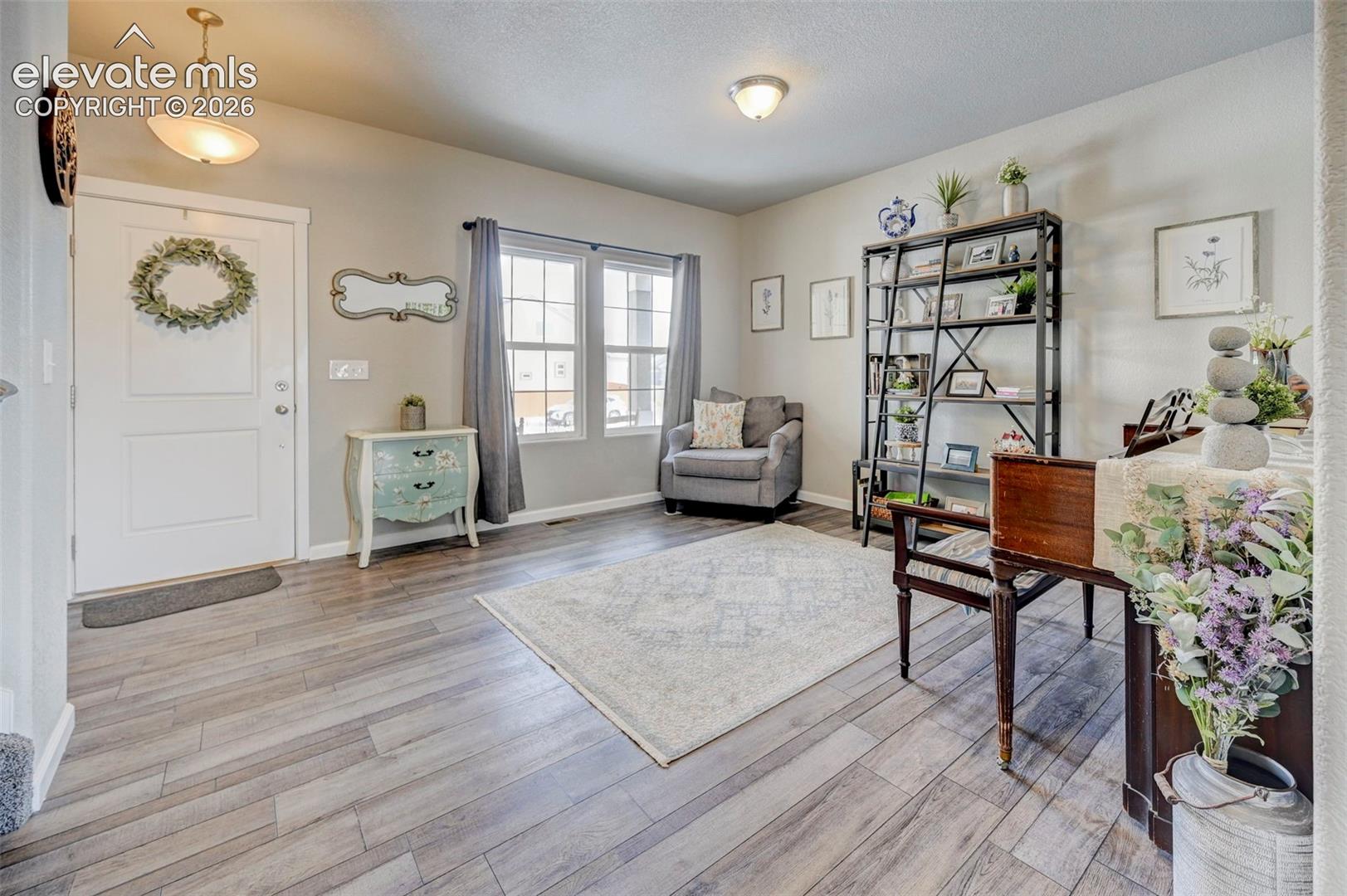 Wood-finish flooring throughout, multi-pane windows, semi-flush mount lighting, and a solid-core panel front door