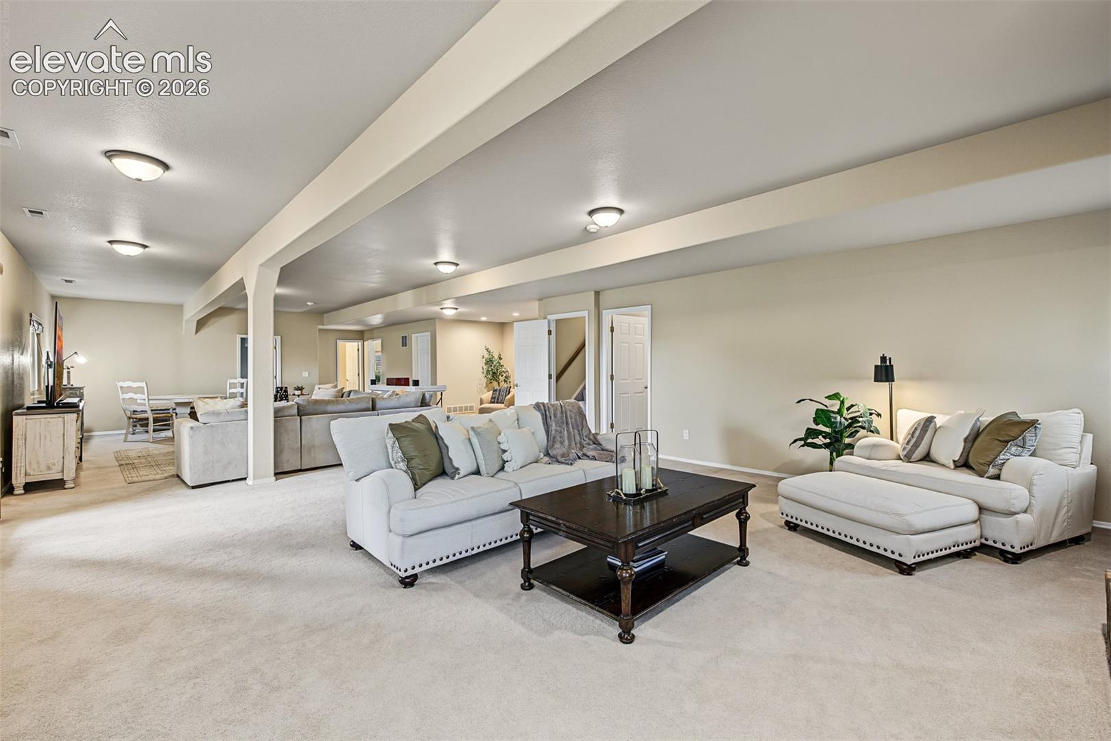 Expansive family room in the full walkout basement, showcasing multiple seating areas, neutral carpeting, and an open layout ideal for entertaining and relaxation, with the gas-log fireplace located directly behind this viewpoint.
