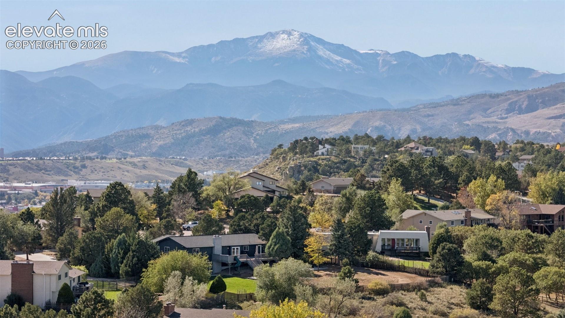 Elevated aerial perspective featuring a mountain backdrop, mature trees, and varied residential architecture