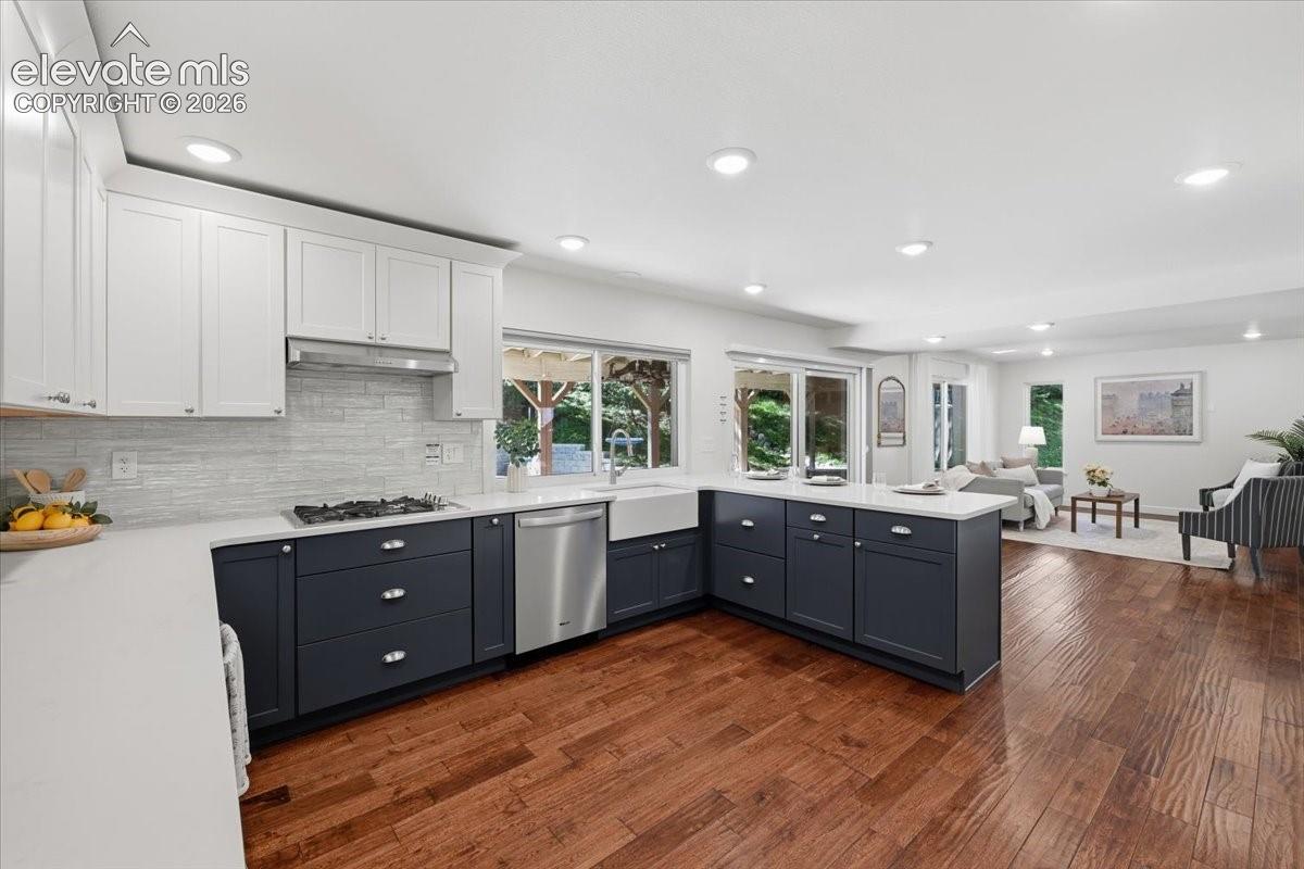 Open concept kitchen featuring two- one cabinetry, a gas range, stainless steel appliances, and a farmhouse sink