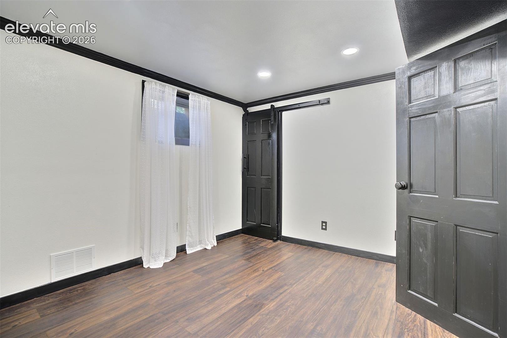 Interior space featuring wood-finish flooring, dark-painted trim and doors, recessed lighting, and a sliding barn-style door
