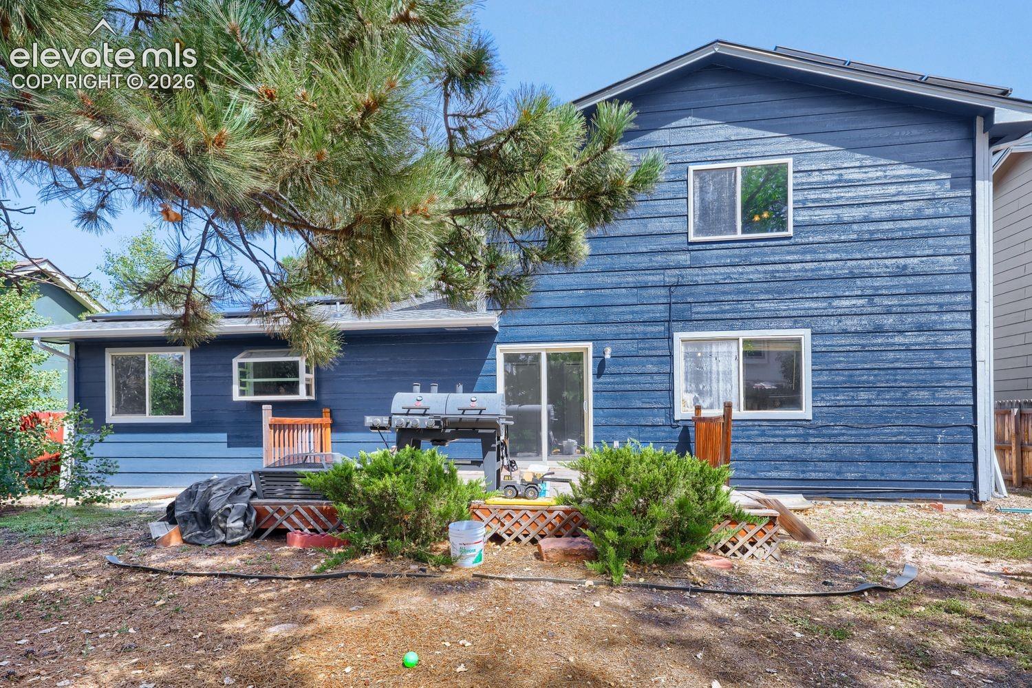 Blue horizontal siding exterior with multiple windows and a sliding glass door