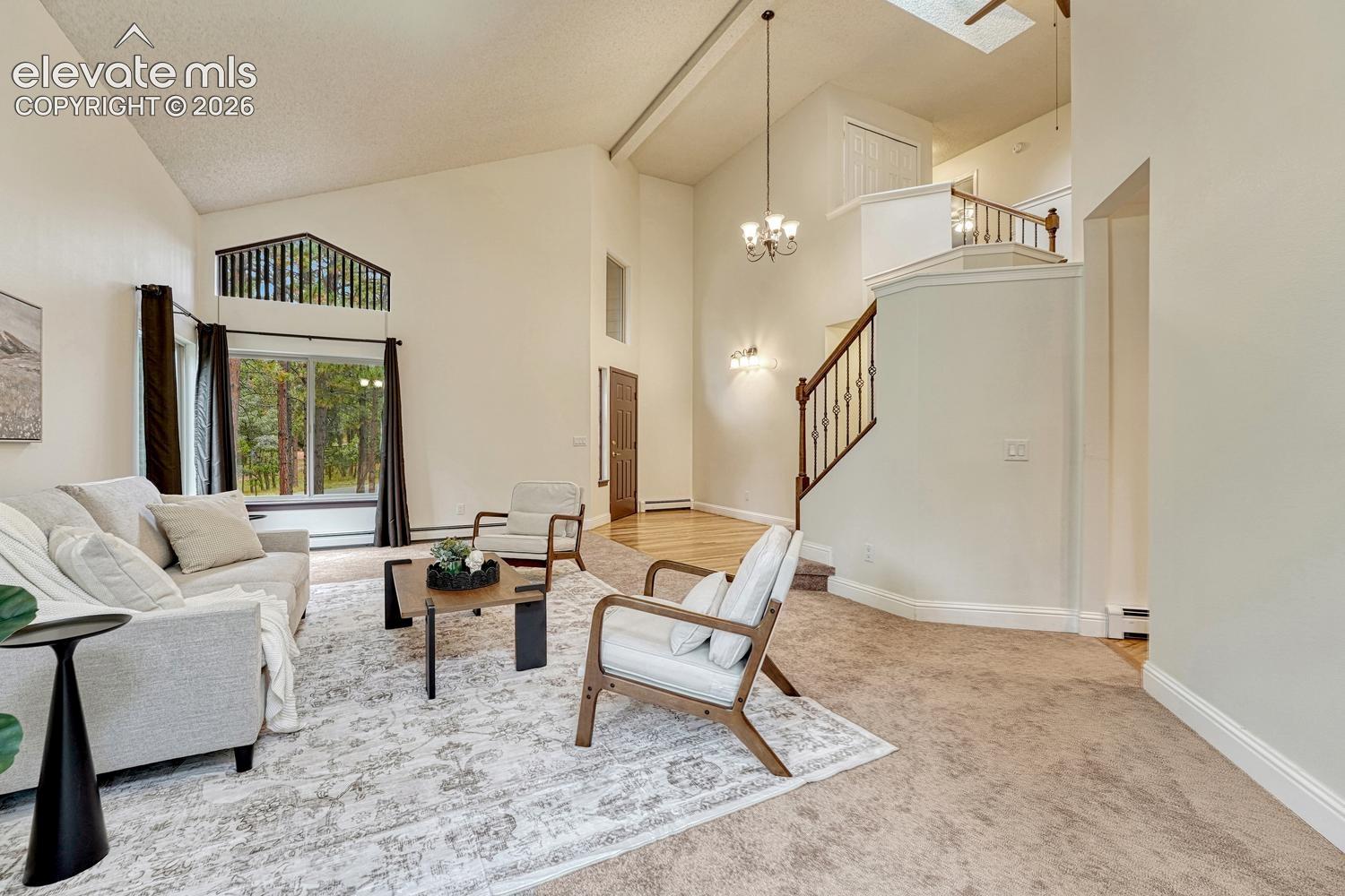 Vaulted ceilings, expansive windows, multi-level staircase with wood railing, pendant lighting, and skylight