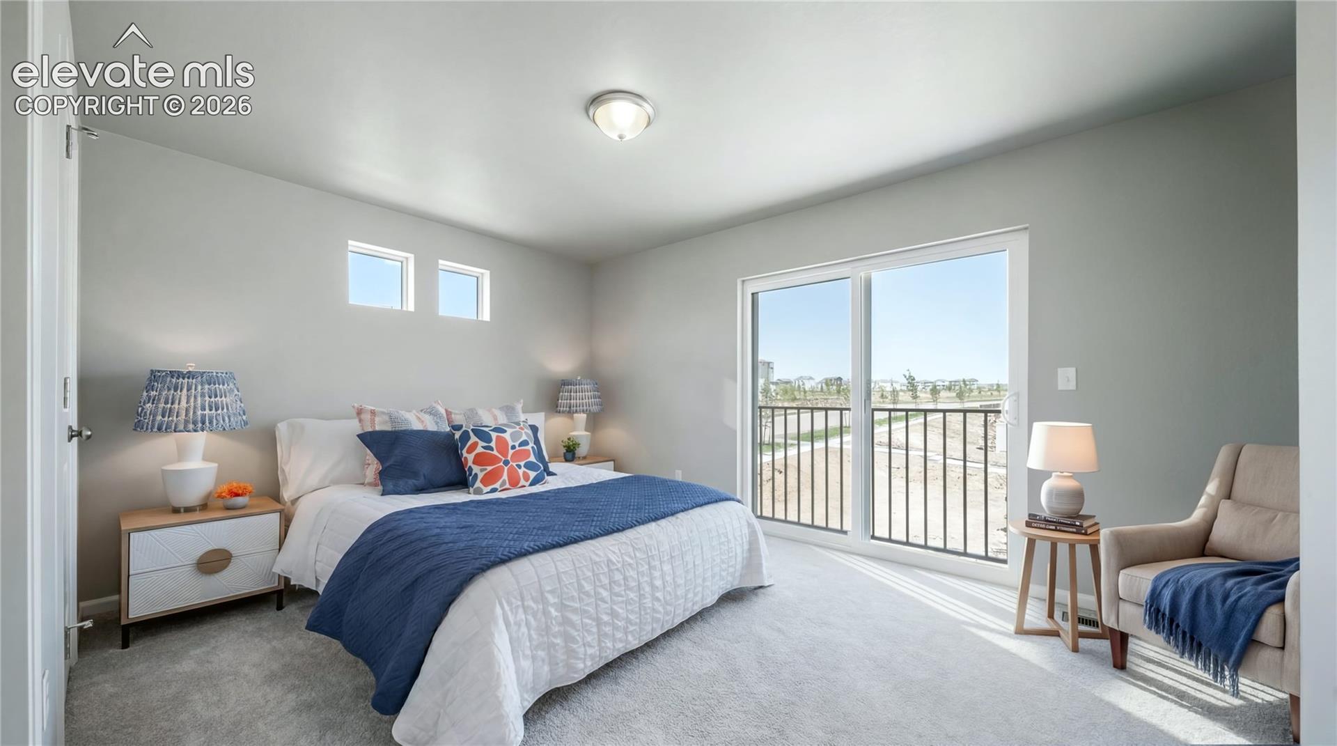 Sliding glass door leading to a black metal balcony railing, neutral wall-to-wall carpeting, high-placed square windows, and a flush-mount ceiling light
*photos of a model home*