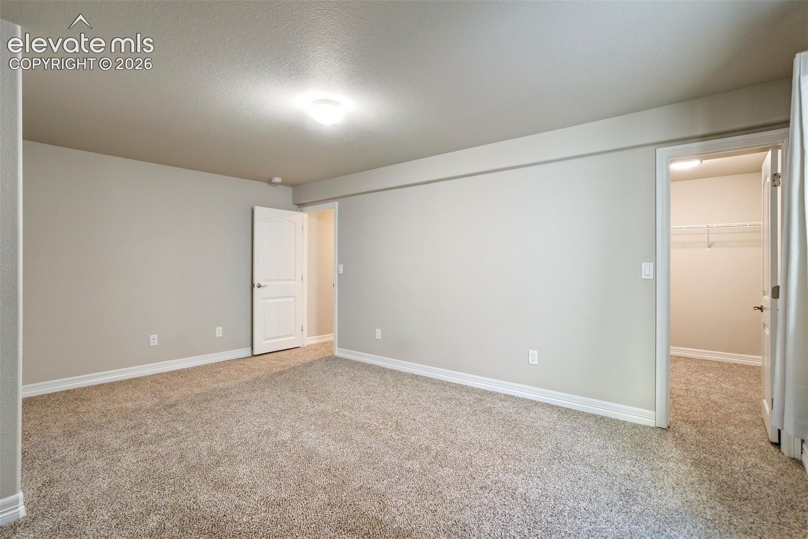 Neutral wall paint, plush carpet flooring, recessed lighting, and a walk-in closet with wire shelving