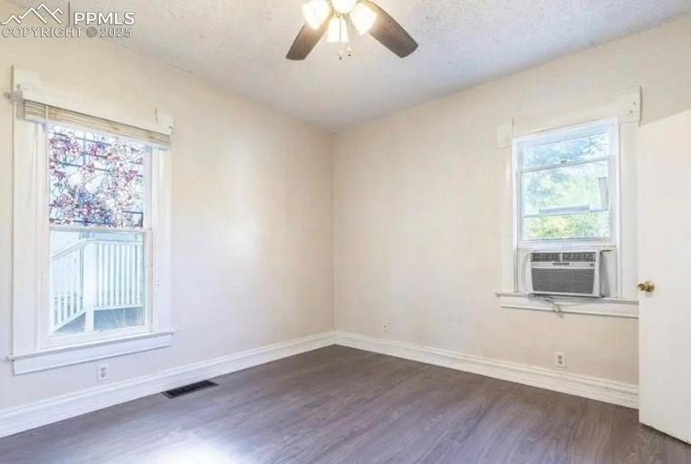 Empty room featuring dark wood-style floors, a ceiling fan, a textured ceiling, and cooling unit