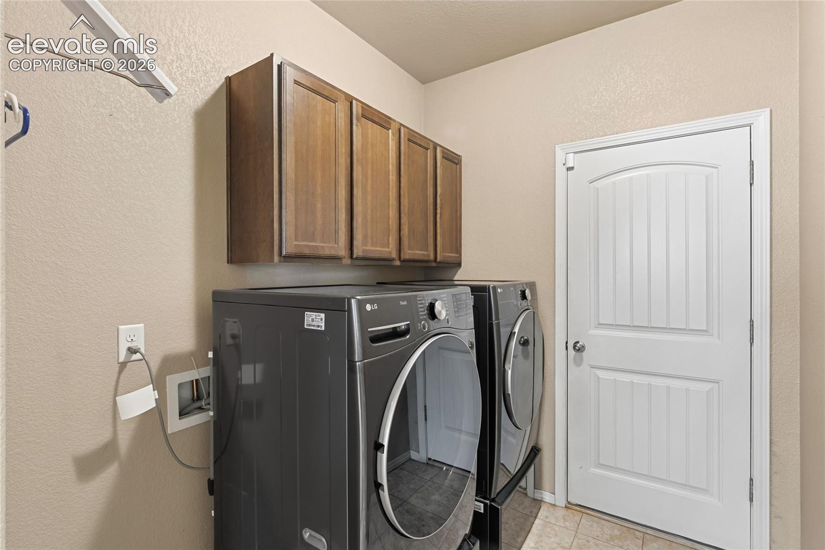 Laundry room featuring built-in wooden cabinetry, a wall-mounted hanging rod, and a multi-panel interior door