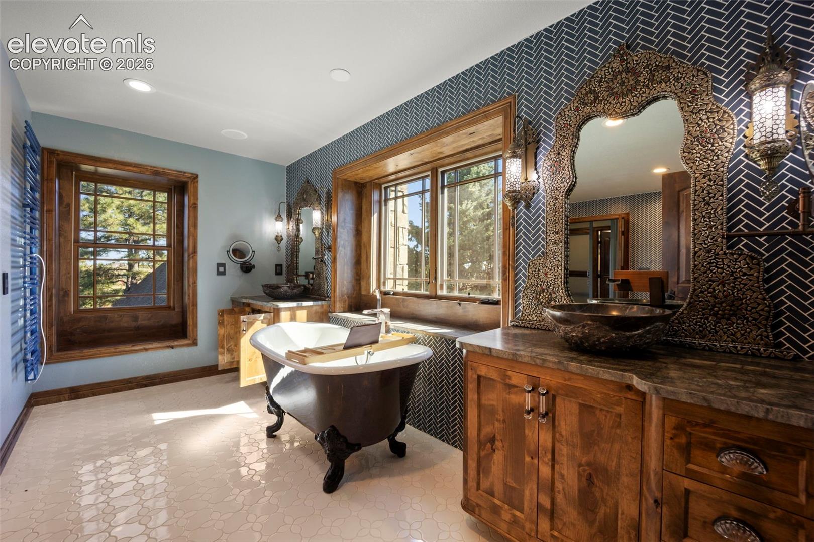 Freestanding clawfoot tub with a light-toned interior, set against a wall featuring dark herringbone-patterned tile