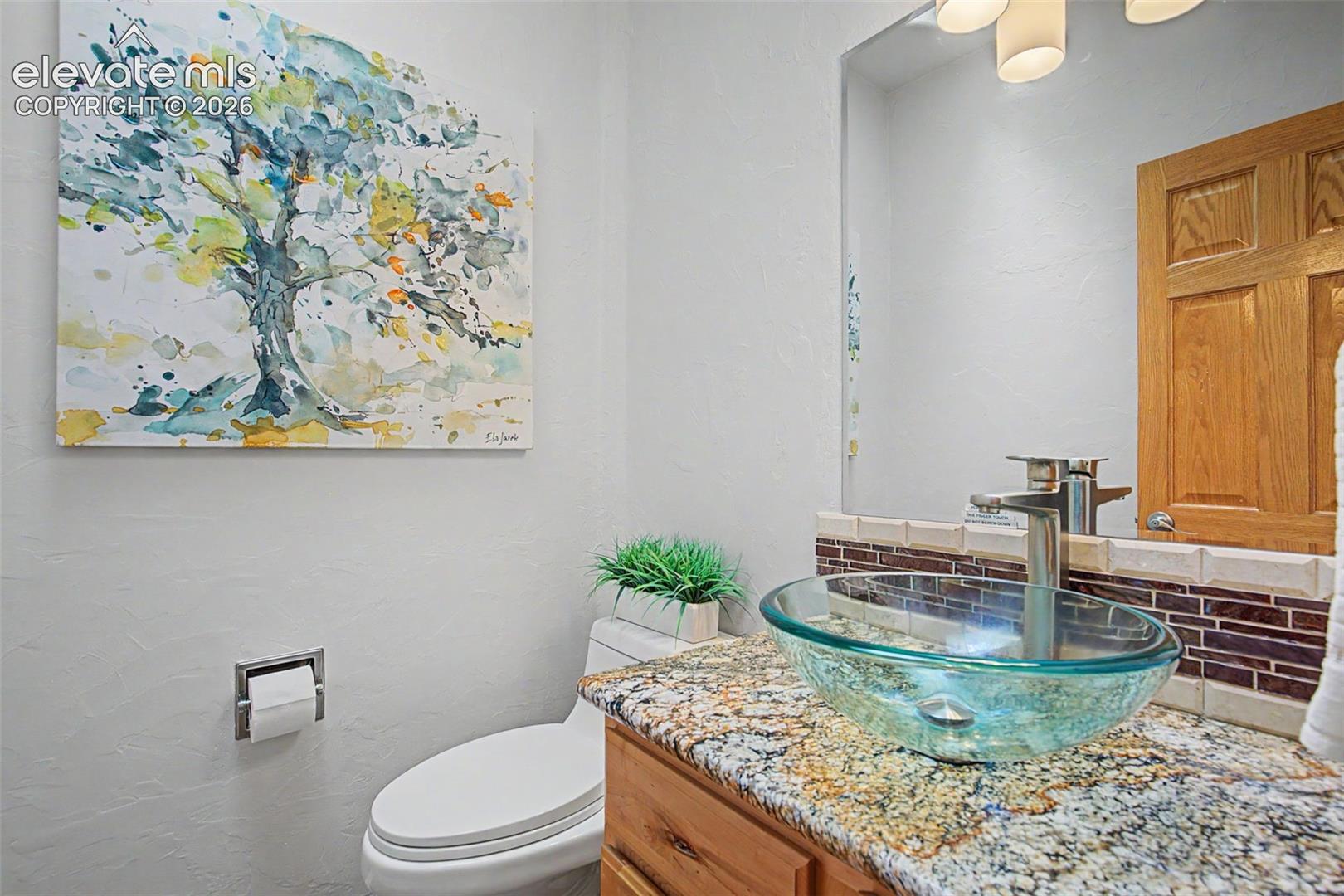 Contemporary vanity featuring a glass vessel sink, granite countertop, and brushed nickel faucet