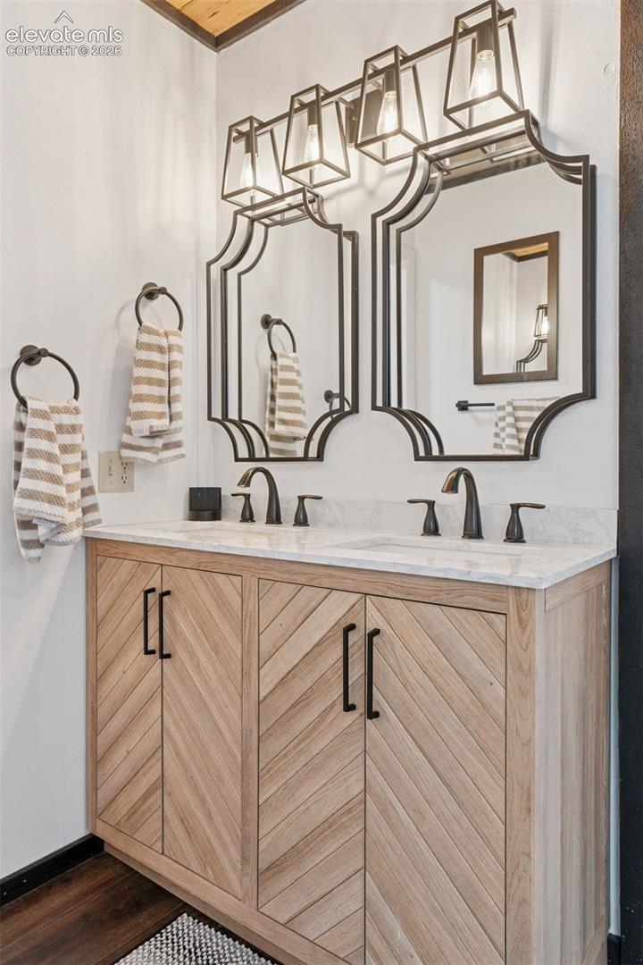 En-suite bathroom with dual sinks, updated vanity cabinetry, and modern lighting fixtures.