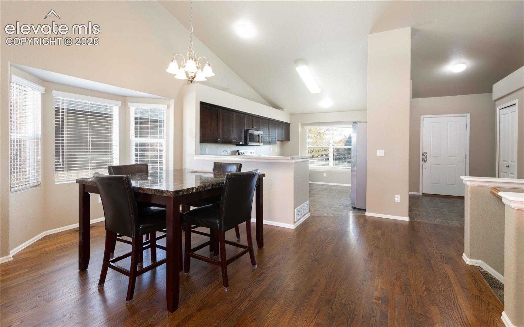 Vaulted ceilings, wood-finish flooring, bay window, built-in dark cabinetry, and recessed lighting
