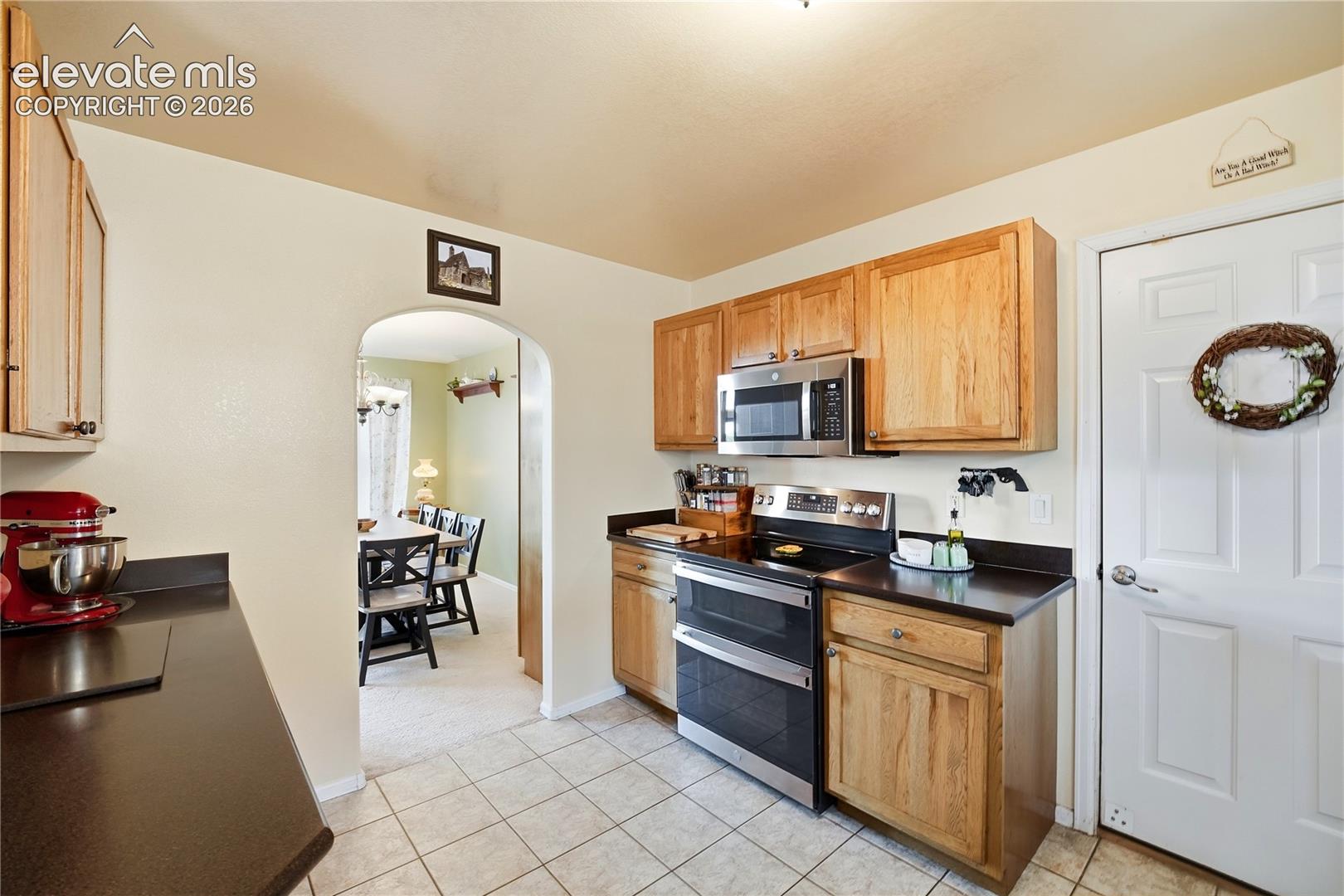 Kitchen featuring wood cabinetry, stainless steel microwave, black electric range, and dark countertops