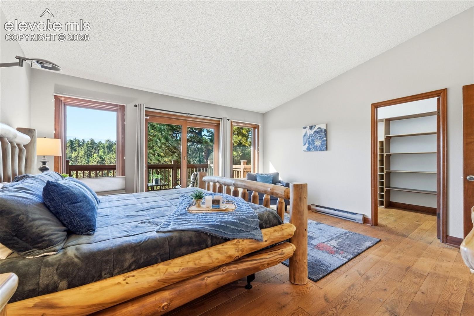Hardwood flooring, vaulted ceiling, built-in shelving, glass panel doors, and a private balcony