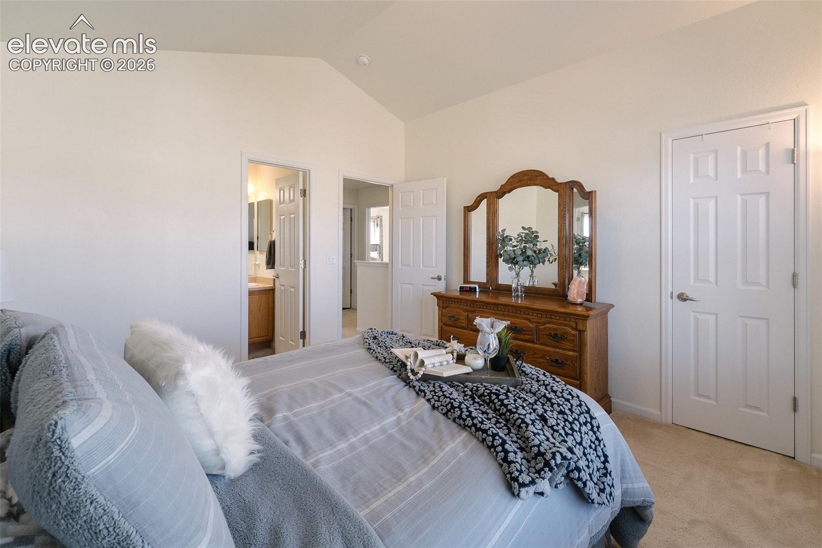 Vaulted ceiling, carpeted flooring, white interior doors, neutral wall tones, and recessed lighting