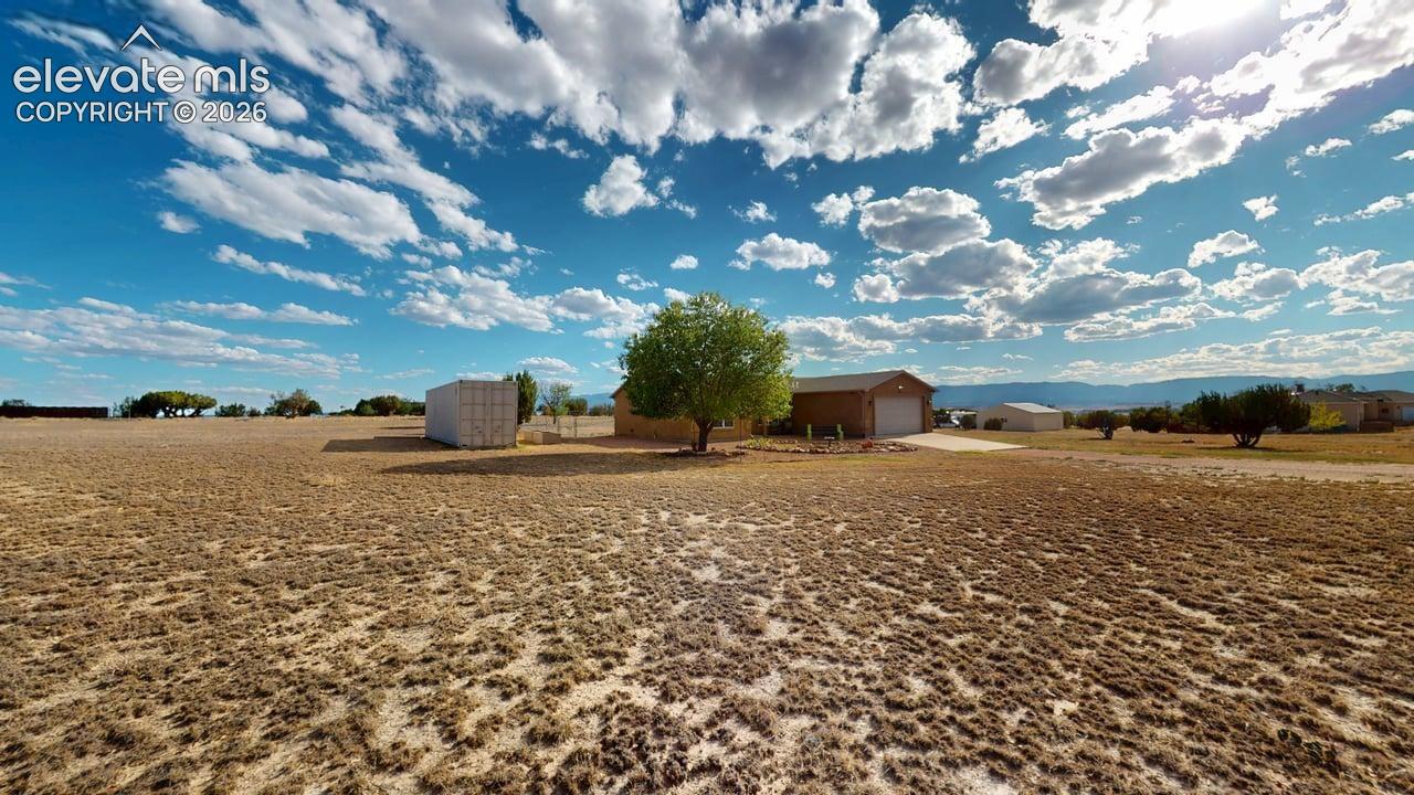 Single-story residence with an attached garage, large open lot, and distant mountain backdrop