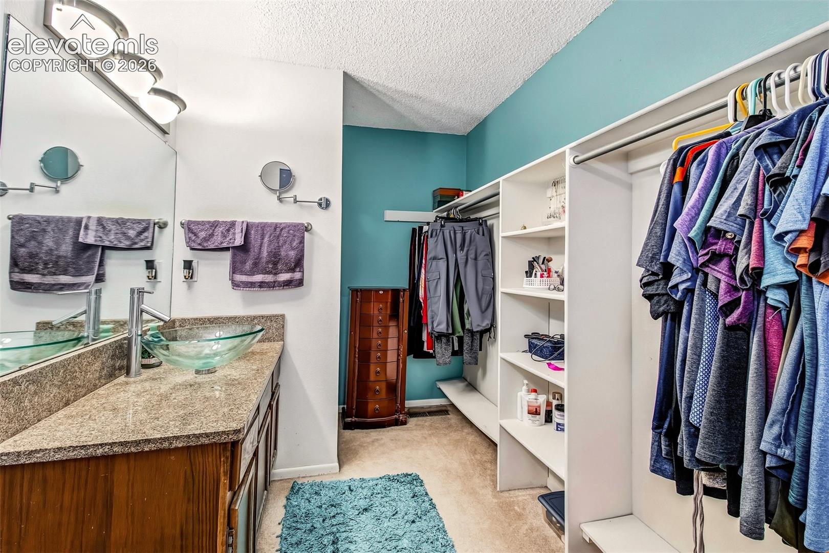 Vanity featuring a vessel sink, stone-finish countertop, and wall-mounted faucet, paired with built-in open shelving and a full-length mirror