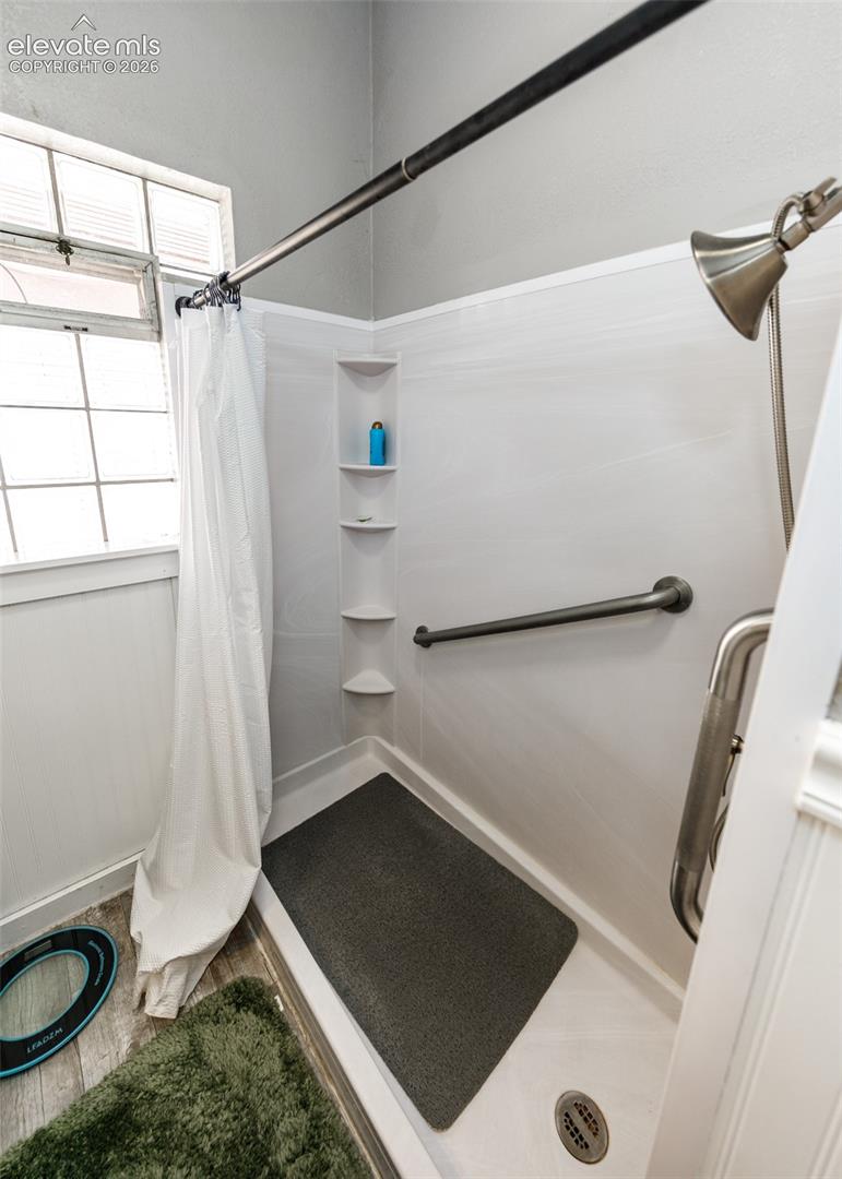 Shower with grab bar, built-in corner shelving, and a handheld shower head