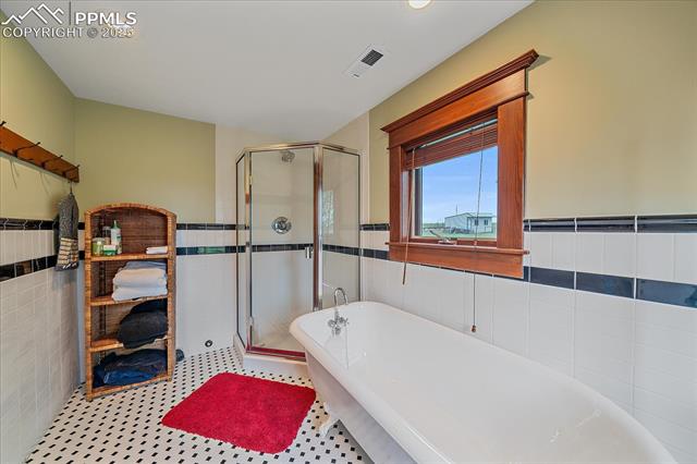 Full bathroom with tile walls, a freestanding bath, a stall shower, a wainscoted wall, and recessed lighting