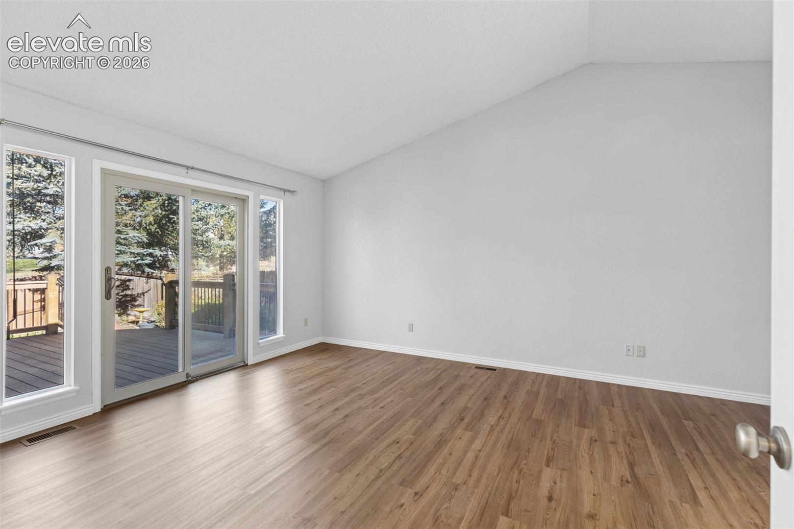 Vaulted ceilings, wood-finish flooring, and sliding glass doors with exterior access