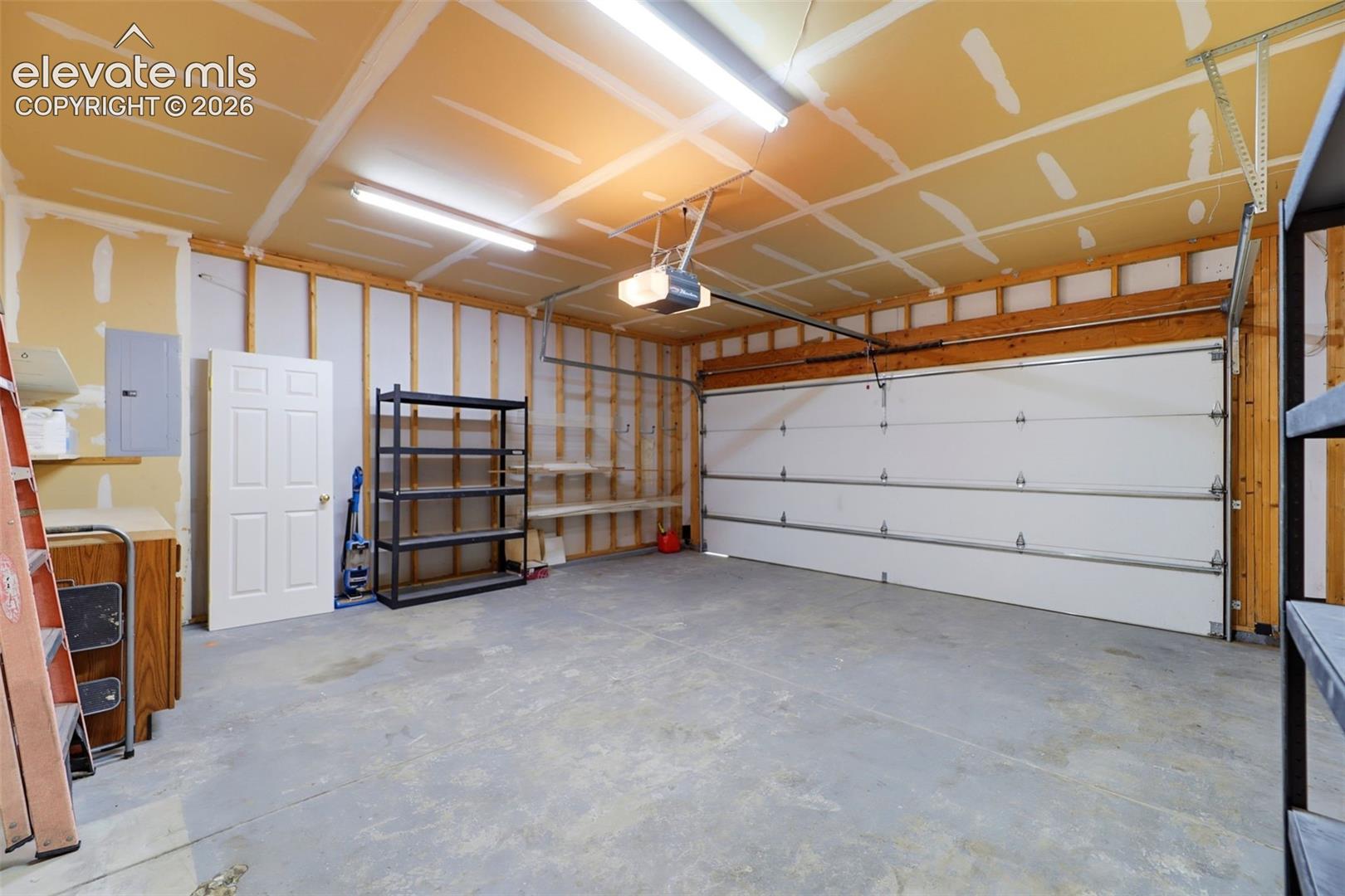 Spacious garage featuring a concrete floor, overhead lighting, and an automatic garage door opener