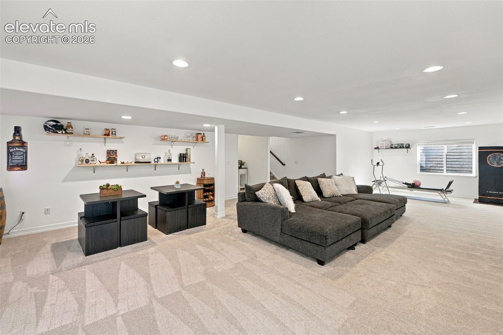 Spacious room featuring wall-to-wall carpeting, recessed ceiling lighting, and built-in wall shelving