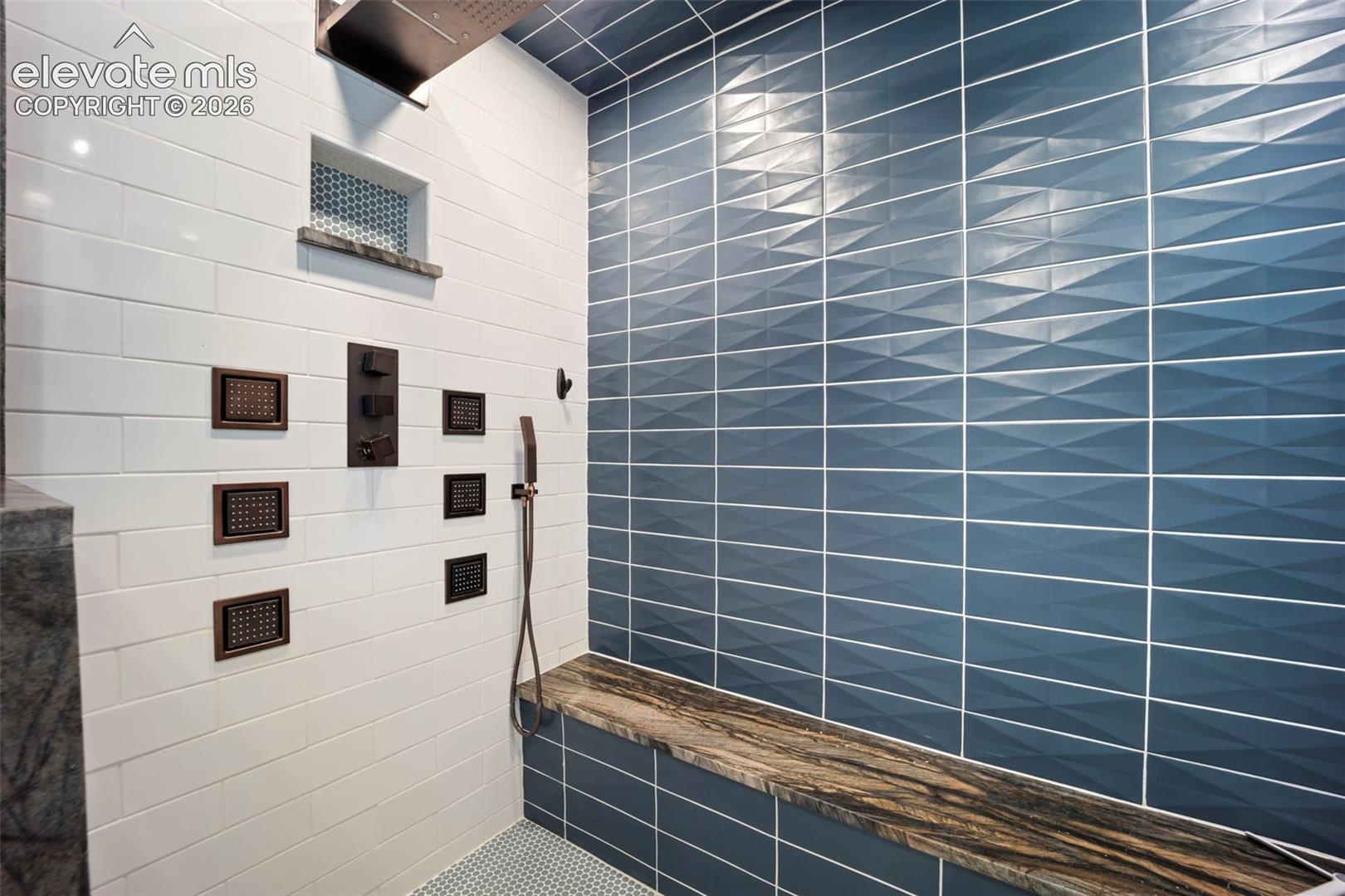 Shower featuring a multi-function shower system with a rainfall showerhead, body jets, and a handheld spray