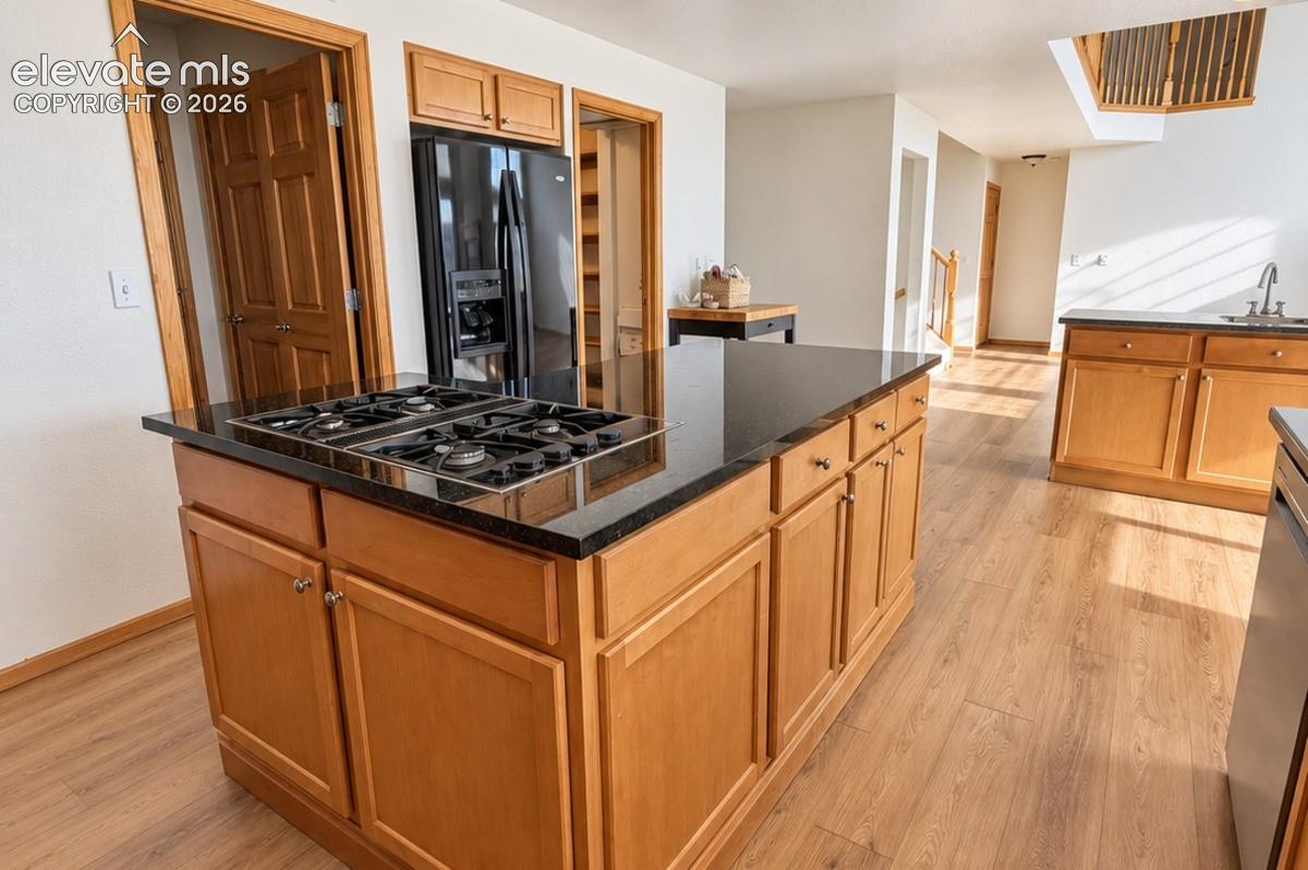 Kitchen island with a built-in gas cooktop, granite countertop, and wood-finish cabinetry