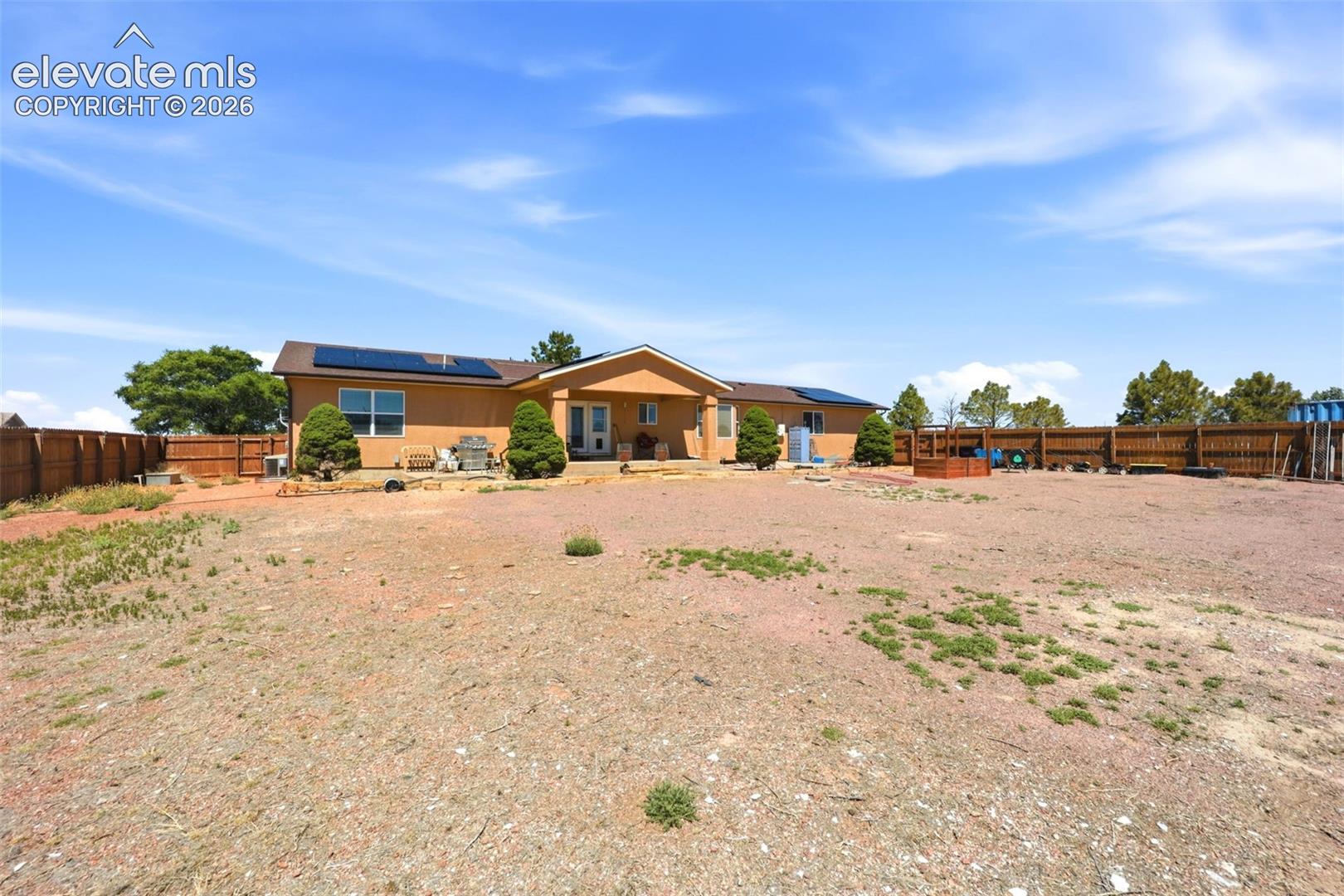 Exterior stucco residence featuring an expansive lot, a covered patio, and a privacy fence