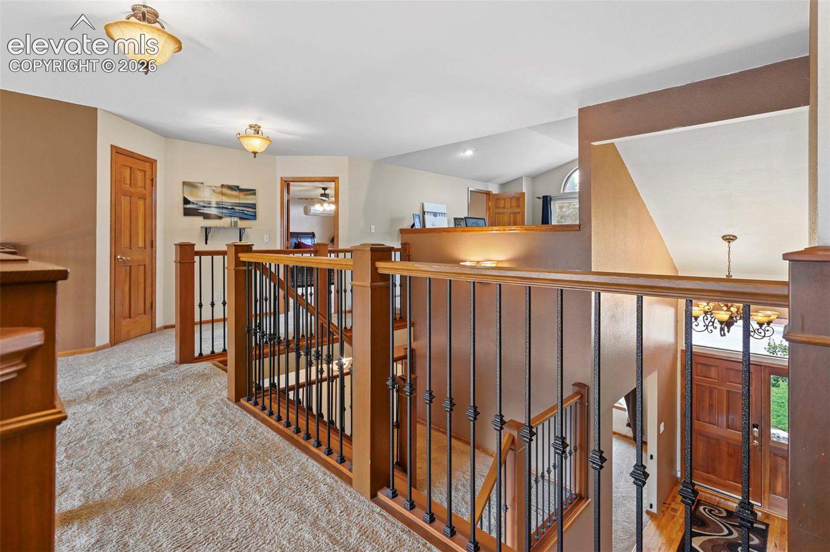 Upper level landing featuring wood-finished doors, carpeted flooring, and decorative semi-flush mount lighting fixtures