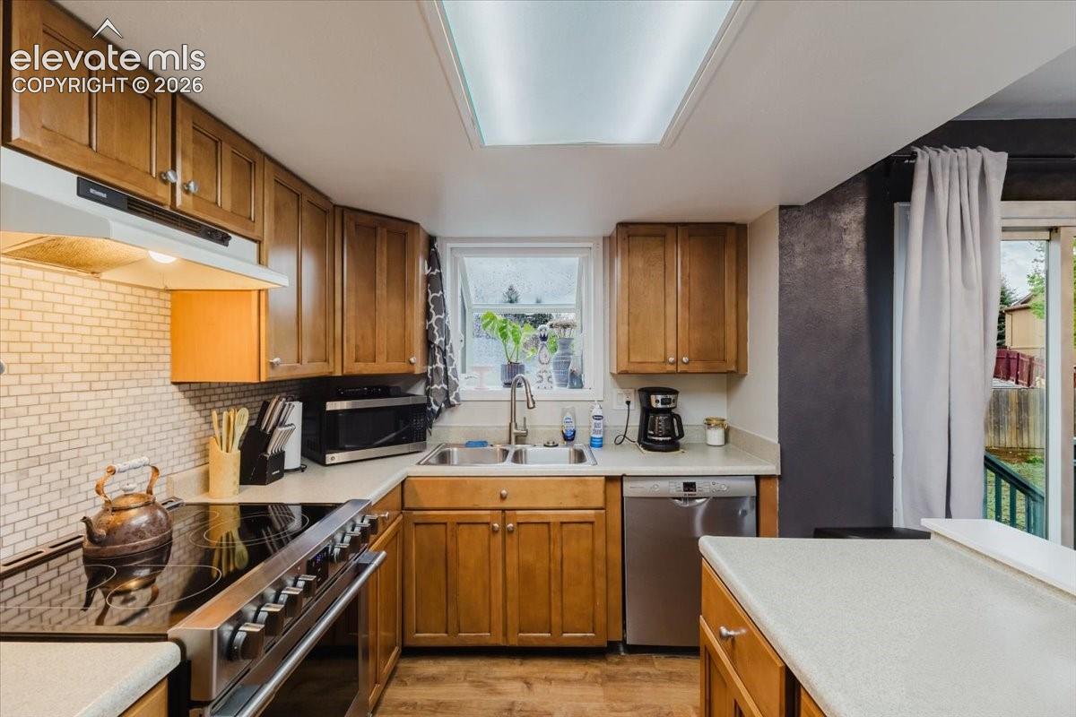 Kitchen featuring wood-finish cabinetry, solid surface countertops, and a subway tile backsplash