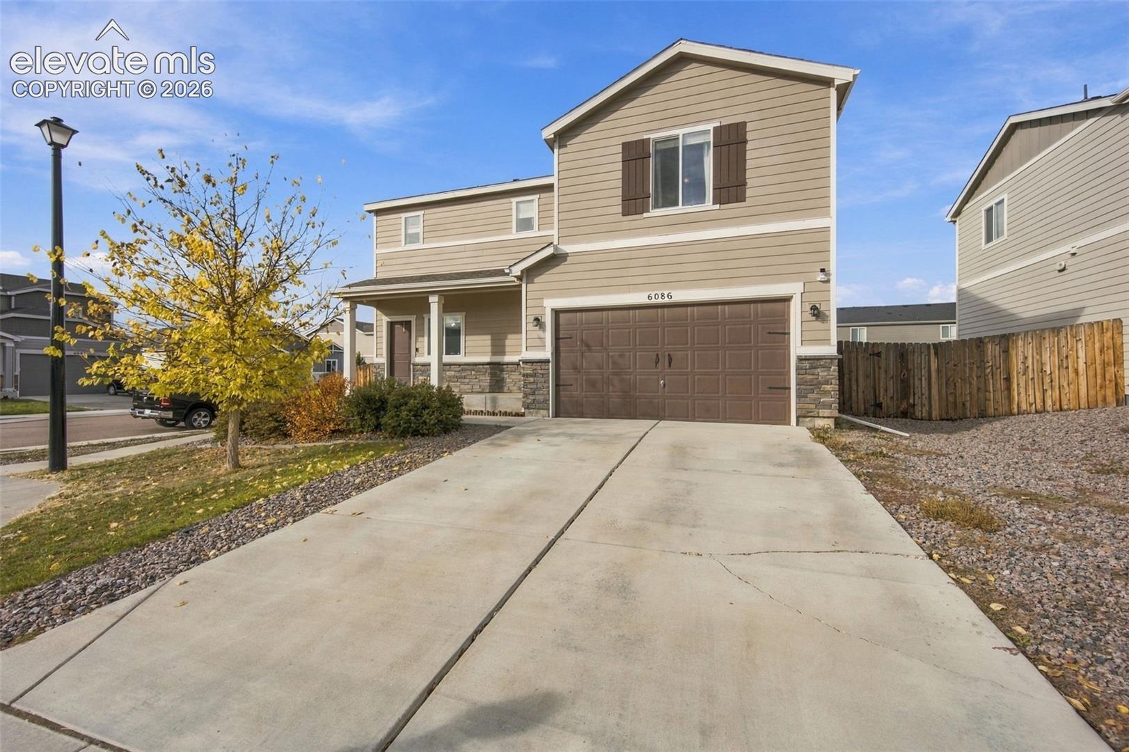 Two-story residence featuring horizontal siding, stone veneer accents, a covered front entryway, and an attached two-car garage