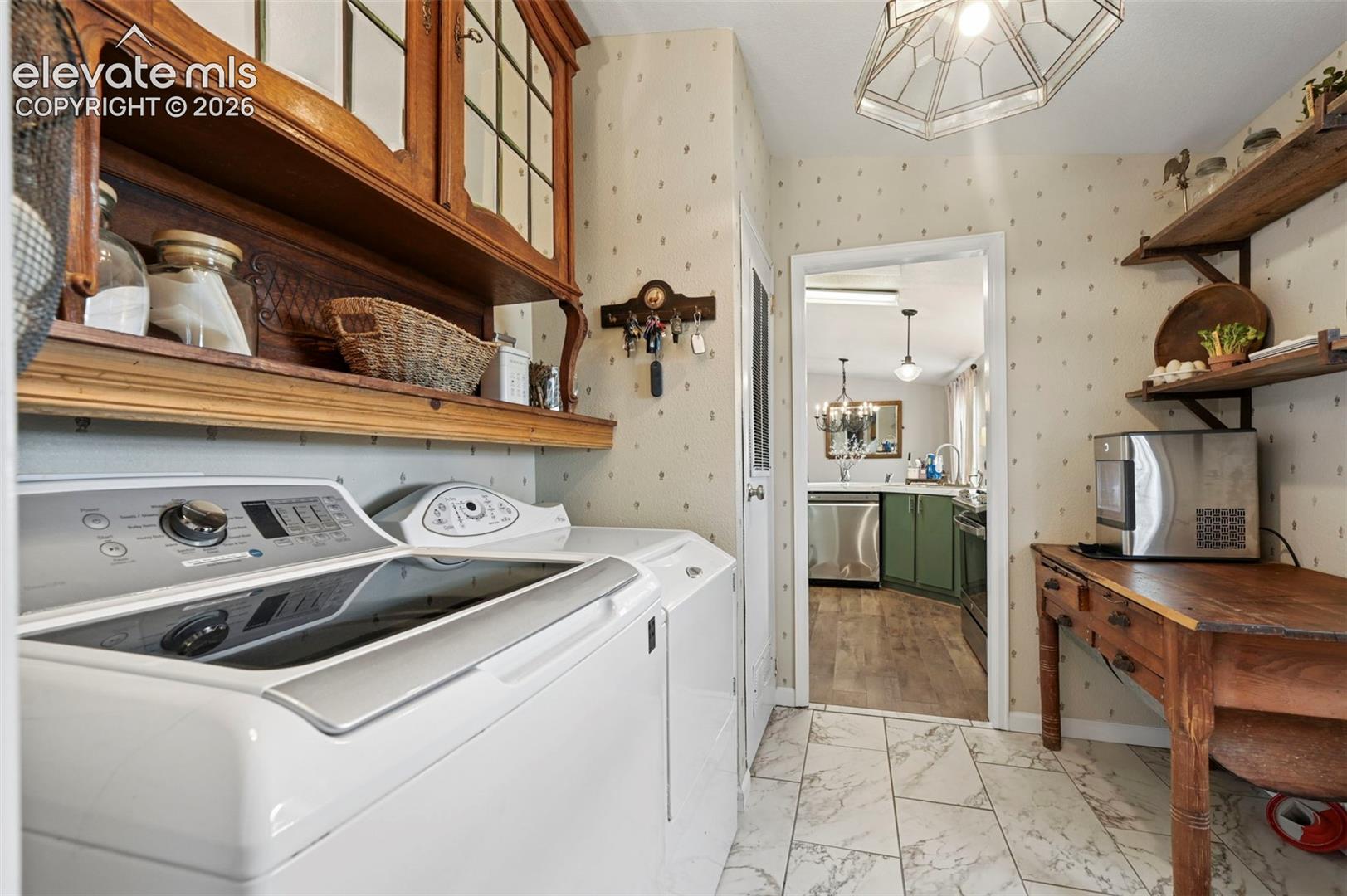 Laundry area featuring built-in wood cabinetry with glass-paneled doors, stone-finish tile flooring, and open shelving