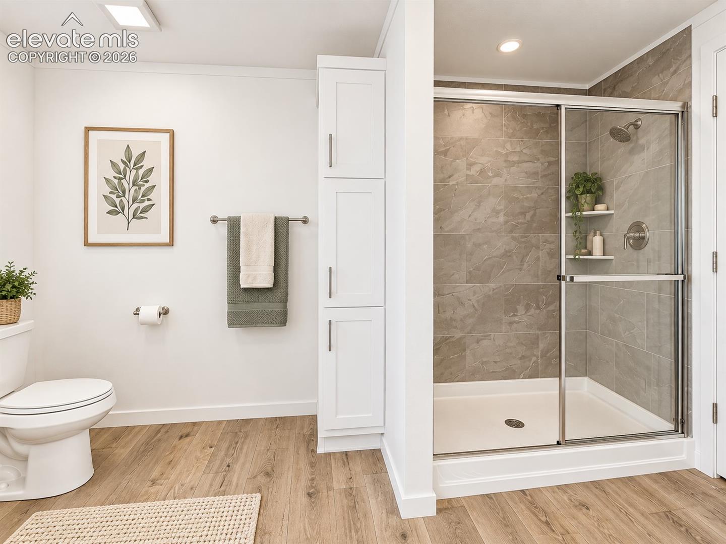 Primary Bathroom – Separate tiled shower with glass enclosure complements the primary bath, while built-in cabinetry adds convenient storage.