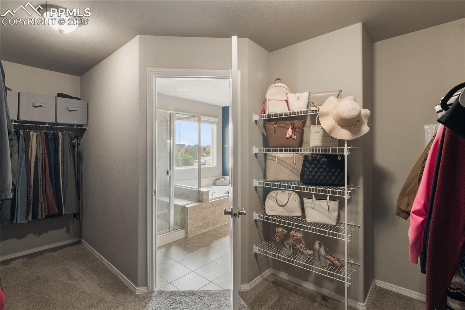 Walk in closet with light colored carpet and light tile patterned floors