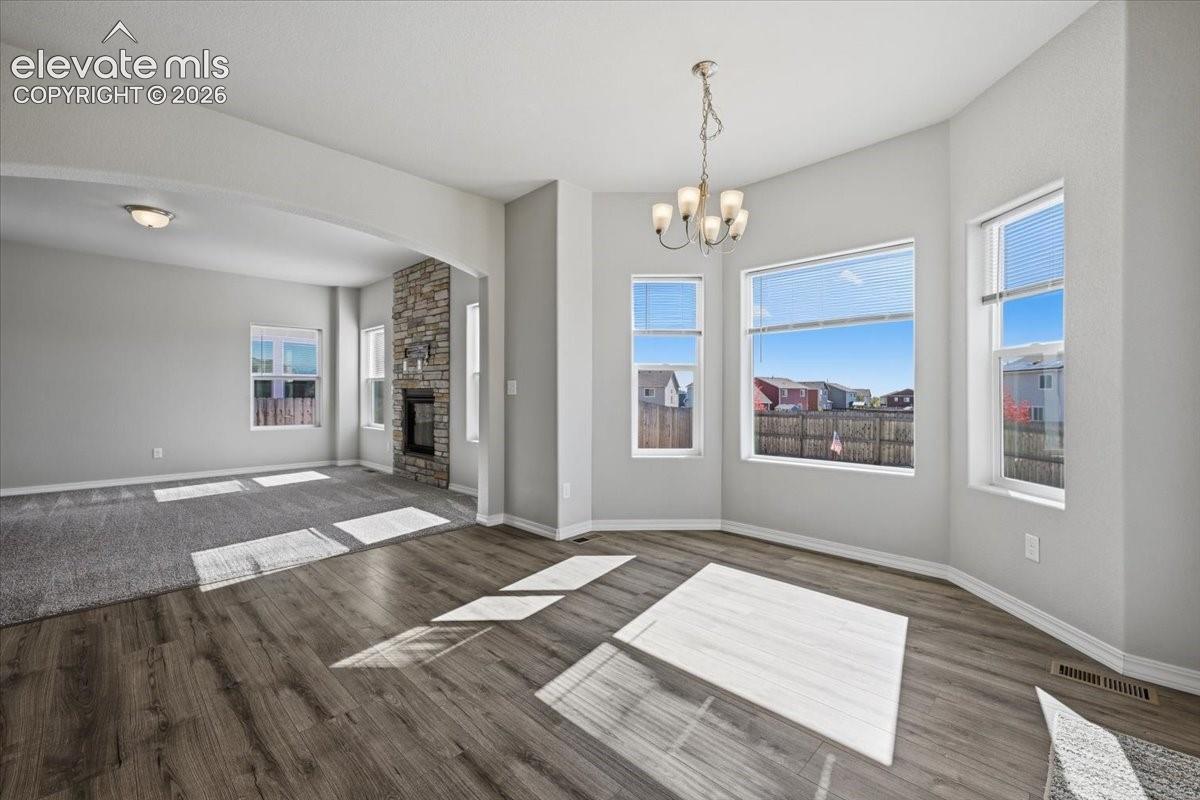 Multi-pane bay windows, wood-finish flooring, stone-veneer fireplace, arched architectural detailing, and tiered chandelier