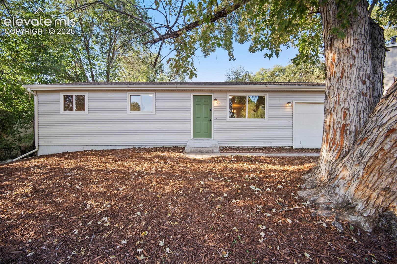 Light-colored horizontal siding exterior with a green entry door
