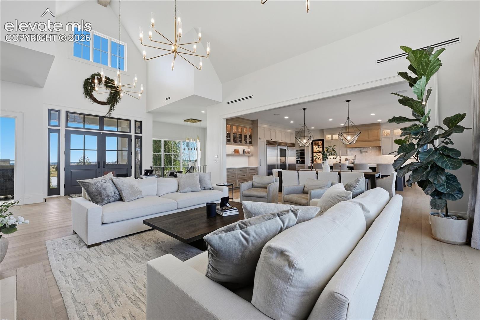 Vaulted ceilings, expansive multi-pane windows, wood-finish flooring, custom modern light fixtures, and built-in kitchen cabinetry