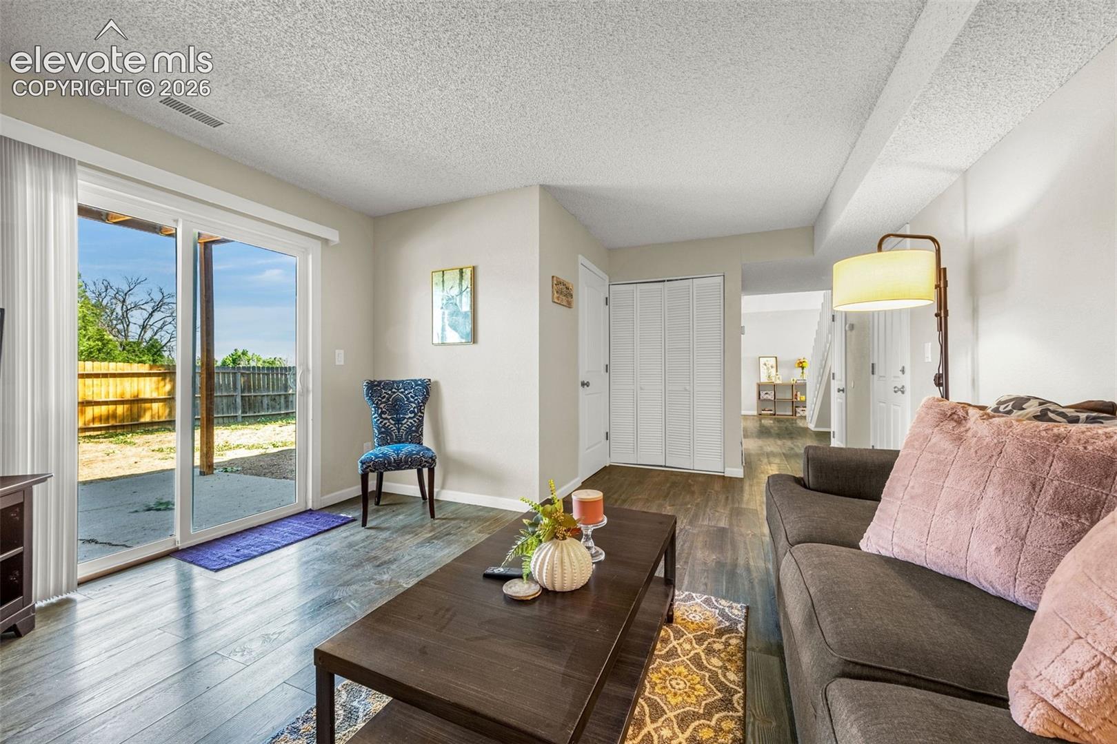 Living area featuring wood-finish flooring, sliding glass patio door, and bi-fold closet doors